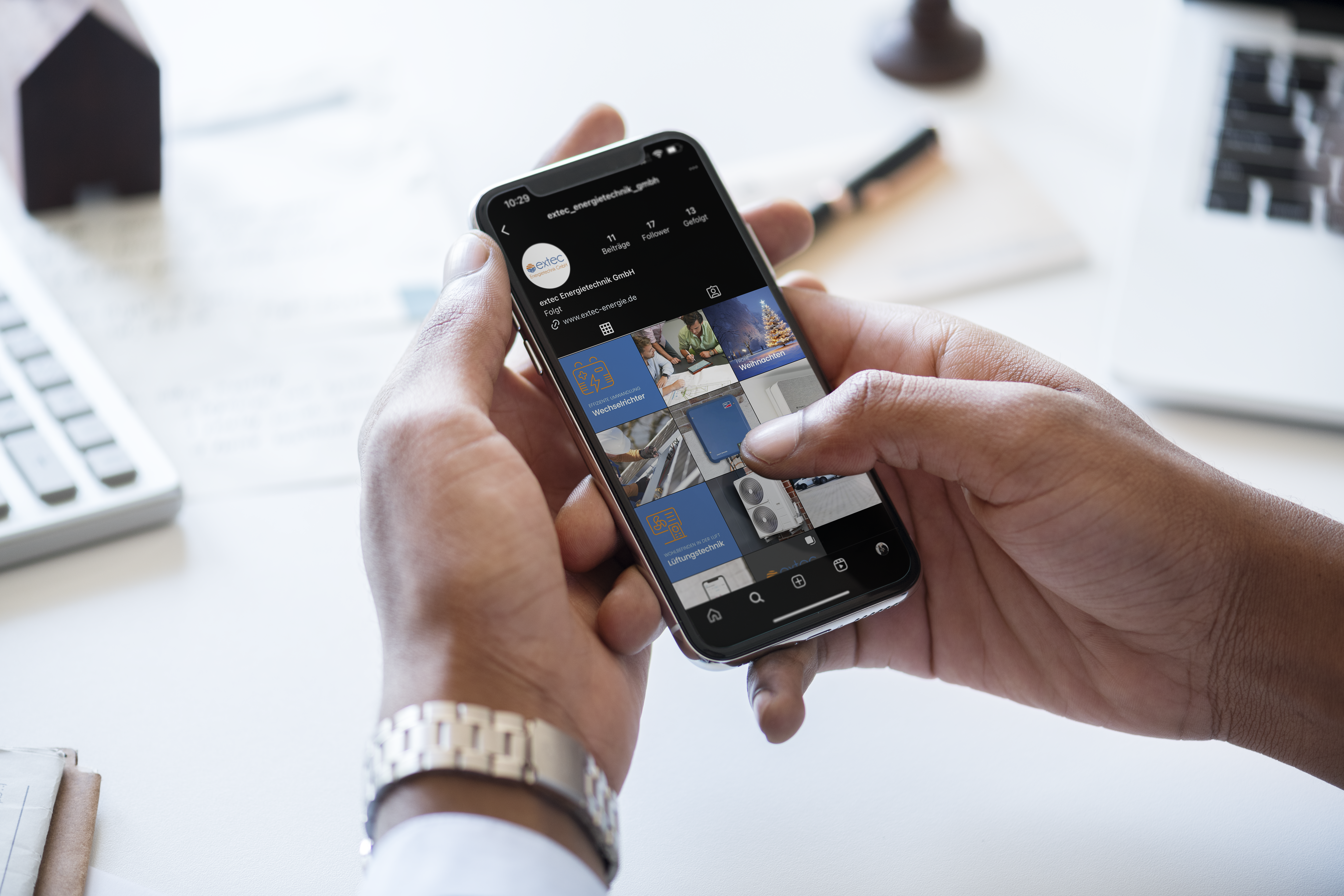 Eine Person scrollt auf einem Smartphone durch die Instagram-Seite eines Unternehmens im Büro.