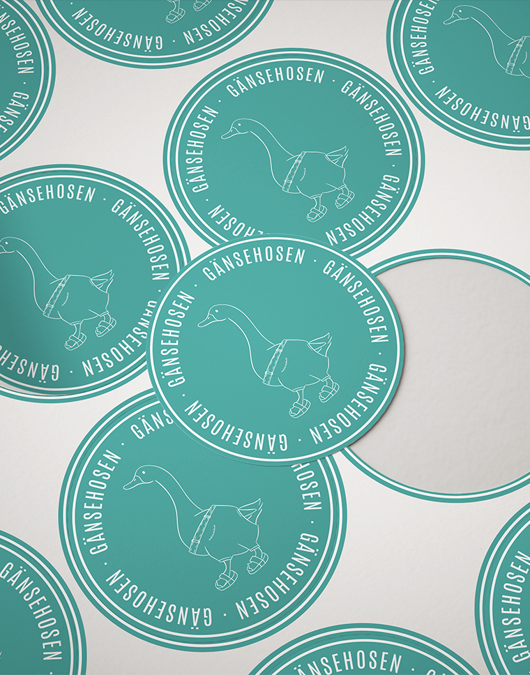 Runde Aufkleber zeigen eine Gans in Hosen mit dem Text "GÄNSEHOSEN" auf türkisfarbenem Hintergrund.