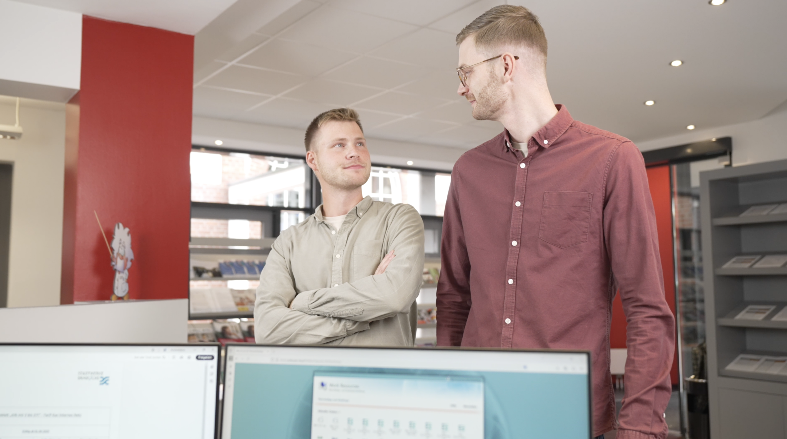 Zwei Männer in einem modernen Büro stehen nebeneinander und unterhalten sich freundlich.